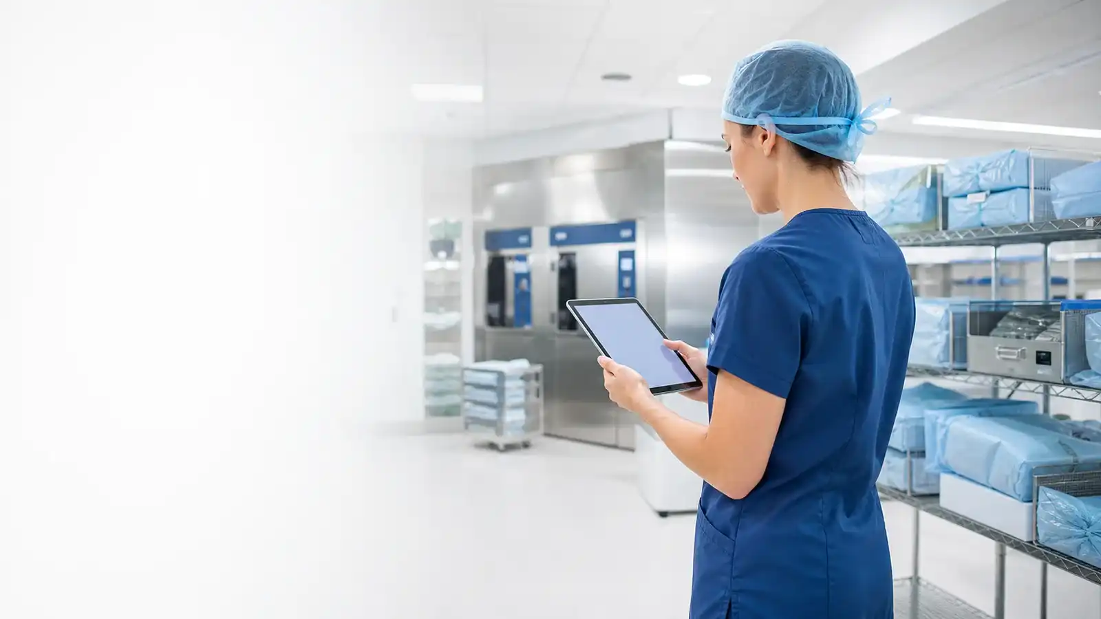 Sterile processing technician reviewing exam prep on a tablet in a clean hospital department